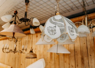 Mehrere stilvolle Lampen hängen von der Decke, darunter eine auffällige Lampe mit floralen Mustern auf einem weißen Schirm und anderen schlichten Formen.