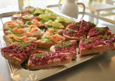 Bunter Teller mit belegten Broten; diese enthalten Lachs, Gemüse und rote Bete, garniert mit frischen Kräutern und auf rustikalem Brot serviert.