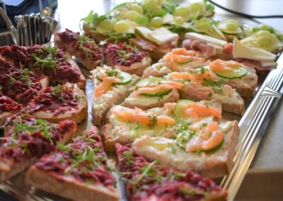 Ein platter mit verschiedenen belegten Brötchen, darunter Rote-Bete-Aufstrich und Lachs mit Gurke; die Brötchen sind garniert mit frischen Kräutern.