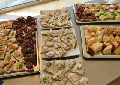 Eine Auswahl an belegten Broten und süßen Snacks auf mehreren Platten. Die Brote sind mit verschiedenen Zutaten, wie Lachs und Kräutern, dekoriert und auf hellen Tellern serviert.