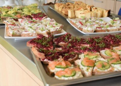 Variationen von belegten Broten auf einem Buffet, darunter Lachs, Schnittlauch und Rote-Beete-Creme auf Vollkornbrot, hübsch angerichtet auf Platten.