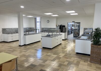 Moderne Küche mit mehreren Küchenzeilen; deutliche Bereiche für Vorbereitungen und Kochstationen sind vorhanden, plus große Fenster, viel Licht und ein offenes Ambiente.