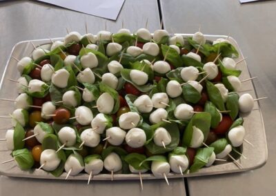 Ein appetitanregender Teller mit Spießen, die Mozzarella-Kugeln, Basilikumblätter und Kirschtomaten verbinden; die Anordnung ist ansprechend und farbenfroh.