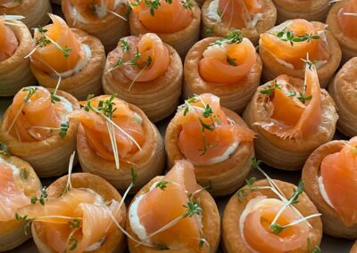 Kleine, gefüllte Blätterteigschalen mit geräuchertem Lachs, Sahne und Kräutern; appetitlich angerichtet und ideal für Fingerfood.