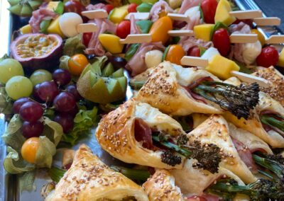 Appetitanregende Platten mit belegten Blätterteigtaschen und Obstsorten auf einem Tablett; die vielfältigen Farben und Formen laden zum Naschen ein.