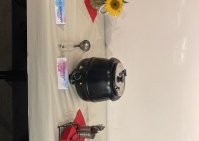Ein gedeckter Tisch mit einer Suppe, frischen Brötchen und buntem Blumenbouquet. Der Tisch ist dekoriert mit Tellern und Besteck.
