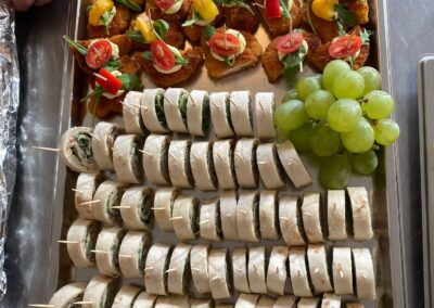 Ein Tablett mit einer Auswahl an Fingerfood; die Appetithäppchen bestehen aus frittierten Brocken, belegt mit Gemüse und serviert mit Trauben.